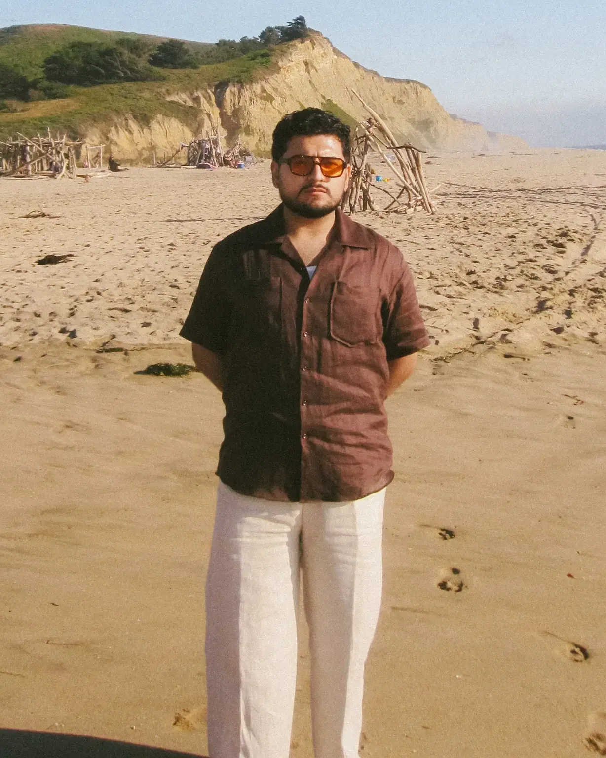 Julian in a short-sleeve shirt and cream trousers on the coast