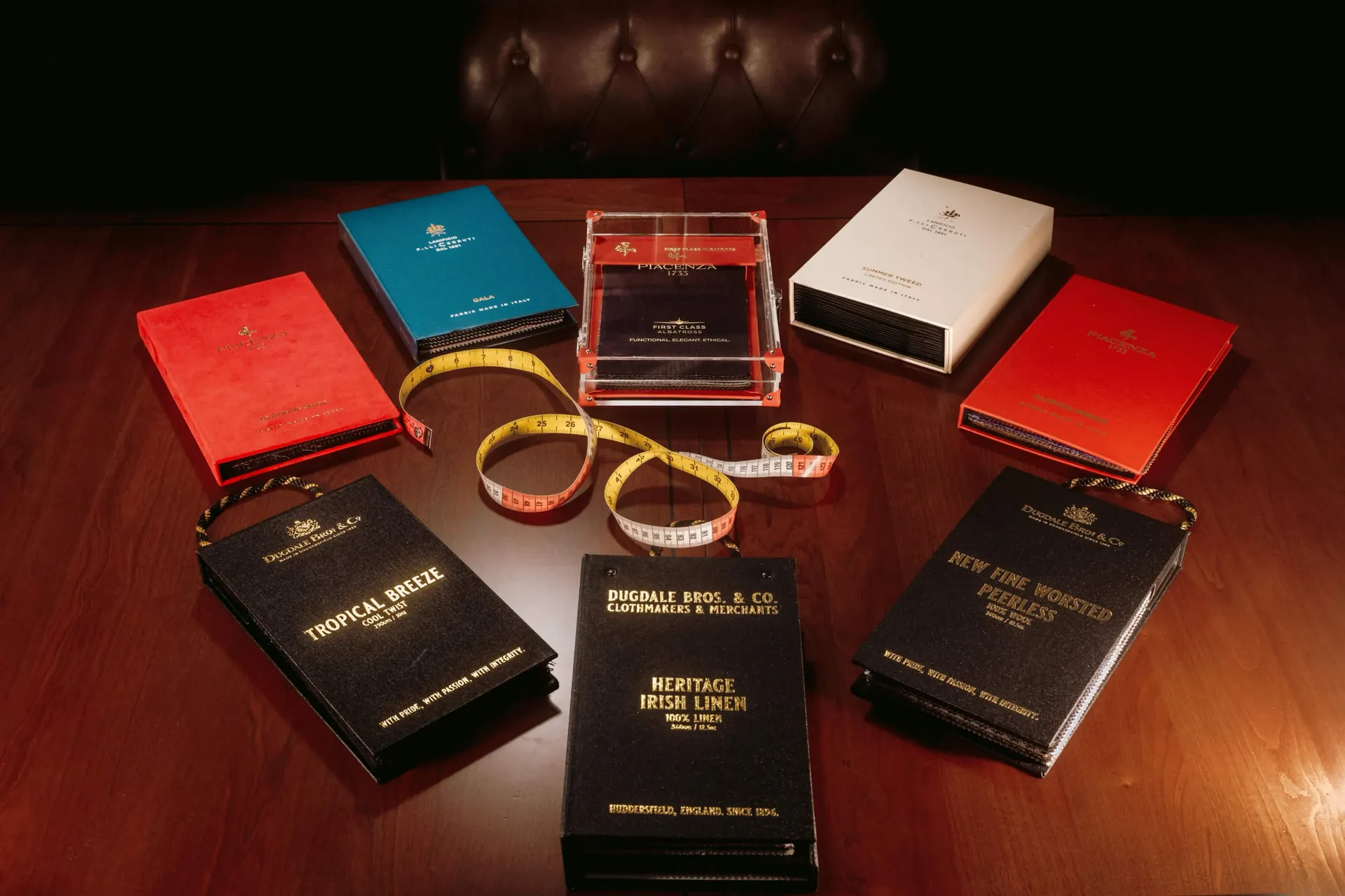 Assortment of Piacenza, Cerruti, and Dugdale Bros fabric swatch books with measuring tape