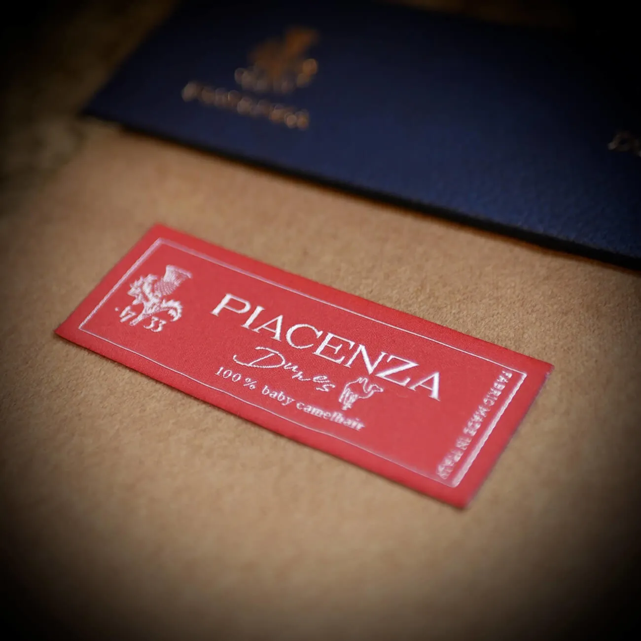 Tailor handling a Piacenza 1733 swatch book — heavyweight bespoke suit cloth at By Fino Los Gatos