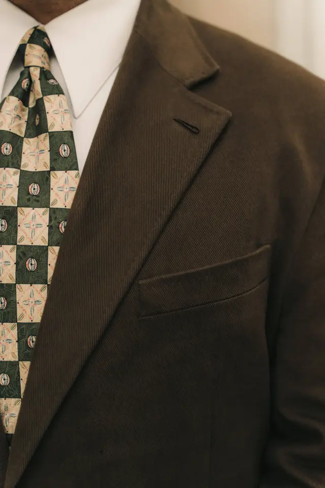 Detail of a brown suit lapel with a patterned silk tie