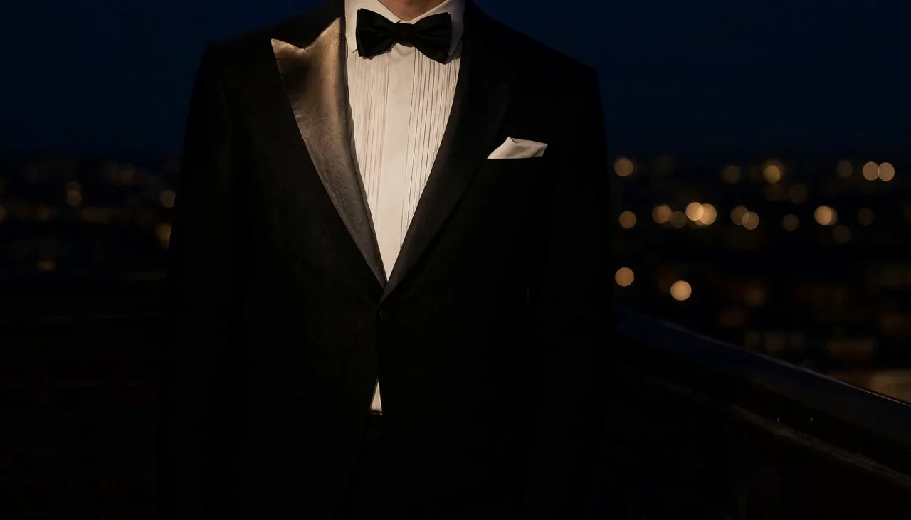A black dinner suit with satin peak lapels and a bow tie at night